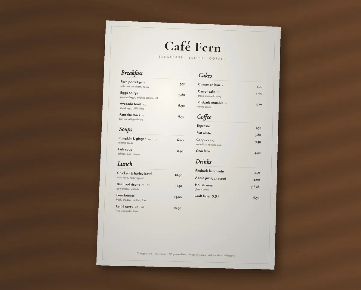 A printed menu for Café Fern lying on a wooden table, photographed with a phone